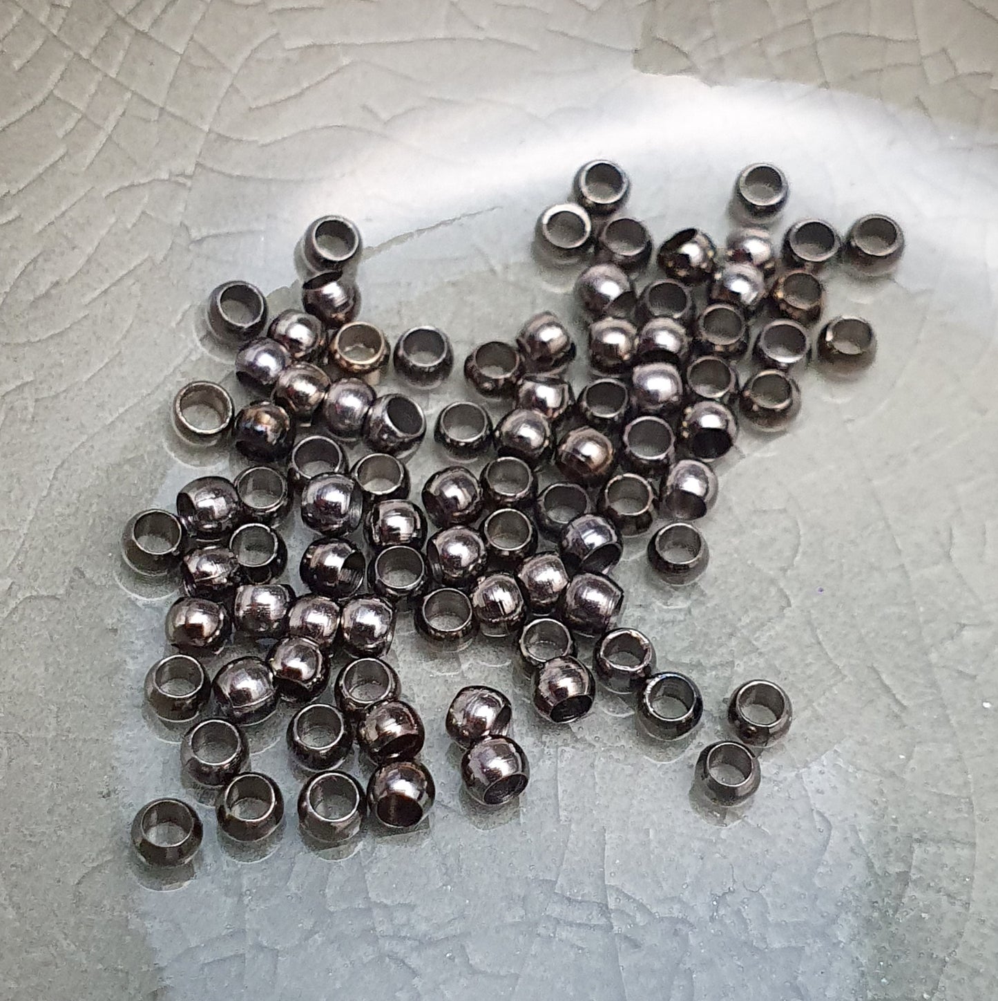 Das Bild zeigt Quetschperlen in Anthrazit (geschwärzt) in Kugelform. Sie eignen sich hervorragend zum Fixieren von Perlen oder zum Bilden von Schlaufen um Verschlüsse anzubringen.
