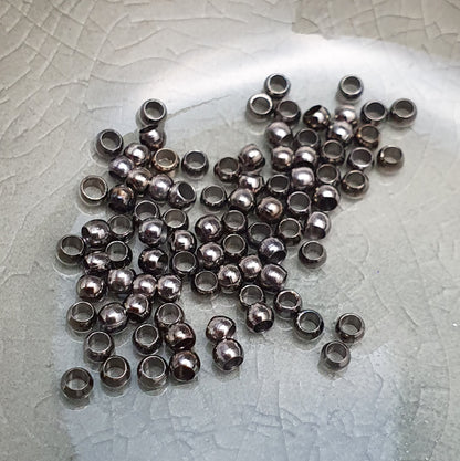 Das Bild zeigt Quetschperlen in Anthrazit (geschwärzt) in Kugelform. Sie eignen sich hervorragend zum Fixieren von Perlen oder zum Bilden von Schlaufen um Verschlüsse anzubringen.