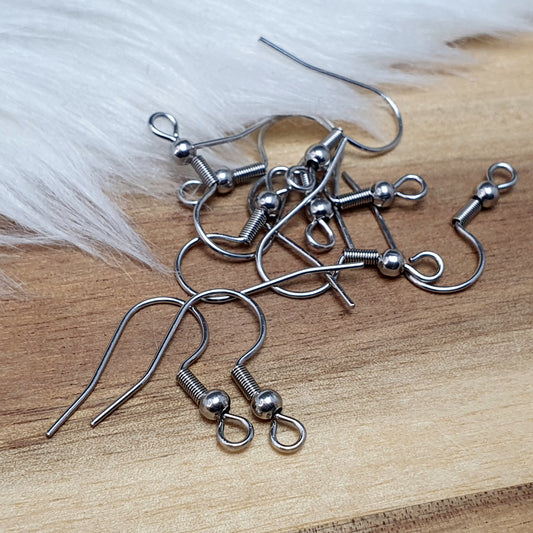 Das Bild zeigt ein Paar French Ohrhaken aus 304 Edelstahl in silberfarbener Optik. Die Haken haben eine geschwungene Form mit einer kleinen Kugel nahe der Öse, die zur Befestigung von Anhängern oder Perlen dient. Die Oberfläche ist glatt und glänzend, was ihnen ein edles und modernes Aussehen verleiht. Die stabilen Haken sind leicht gebogen, sodass sie bequem ins Ohr eingeführt werden können.