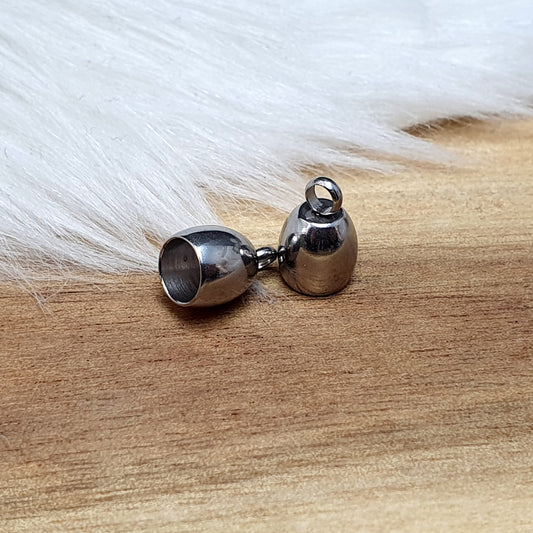 Das Bild zeigt zwei Endkappen aus hochwertigem 304 Edelstahl mit einem Durchmesser von 5 mm. Jede Endkappe verfügt über eine feste Öse, die für einen sicheren Halt sorgt und das Anbringen von Verschlüssen oder Anhängern erleichtert. Die silberfarbene Oberfläche der Endkappen verleiht ihnen ein elegantes und modernes Aussehen. Diese Endkappen sind ideal für die Fertigung von Quasten oder als Abschluss für dicke Bänder aus Materialien wie PU oder Leder, um ein professionelles Finish zu erzielen. Die kompakte 