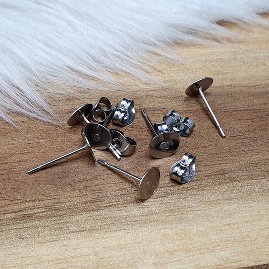Das Bild zeigt Ohrstecker mit runder Klebeplatte aus Edelstahl in silber mit Flügelmuttern.