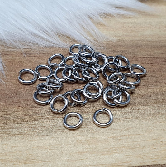 Das Bild zeigt 30 offene Biegeringe aus hochwertigem Edelstahl, die in zwei Größen (Ø 5mm und Ø 6mm) angeordnet sind. Die Biegeringe haben eine glänzende, silberfarbene Oberfläche und sind offen, was ihre einfache Handhabung für das Verbinden von Schmuckkomponenten ermöglicht. Die Ringe sind perfekt für die Herstellung von individuellen Schmuckstücken wie Armbändern, Halsketten oder Ohrringen und bieten eine zuverlässige und langlebige Lösung für kreative Projekte.